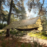 DD Hammocks Tarp 3x3 Pro set up in a forest, showcasing its versatile design and bright sunlight filtering through.
